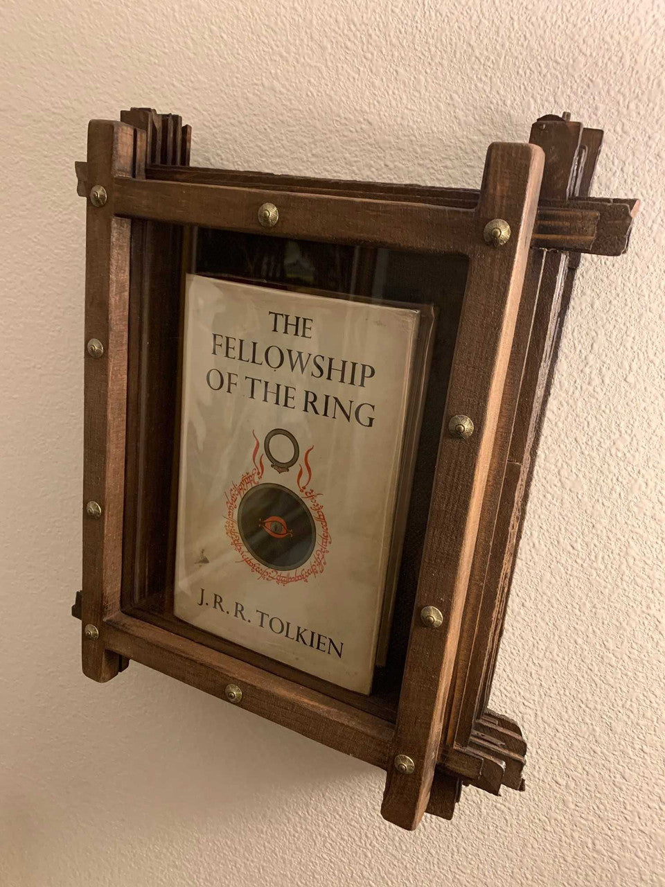 J.R.rR. Tolkien Book Display made of solid wood with glass lid hanging on a creame colored wall.
