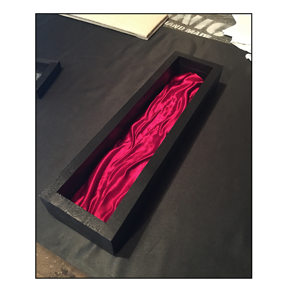 A handcrafted wooden wand collector's display case with a glass lid and satin backing, displayed against a black background.