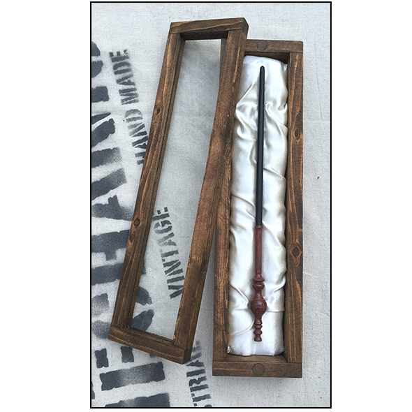A handcrafted brown wooden wand collector's display case with a glass lid and satin backing with wand, displayed laying against a white background.