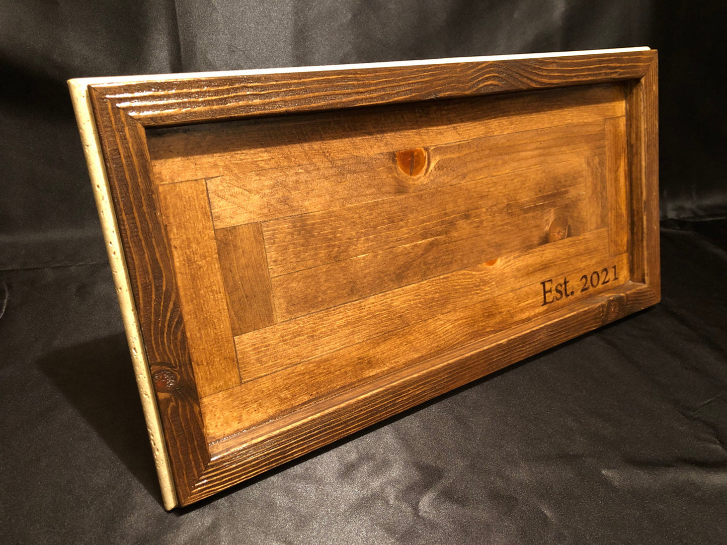 Side view of solid wood charcuterie board with travertine inlay against black background
