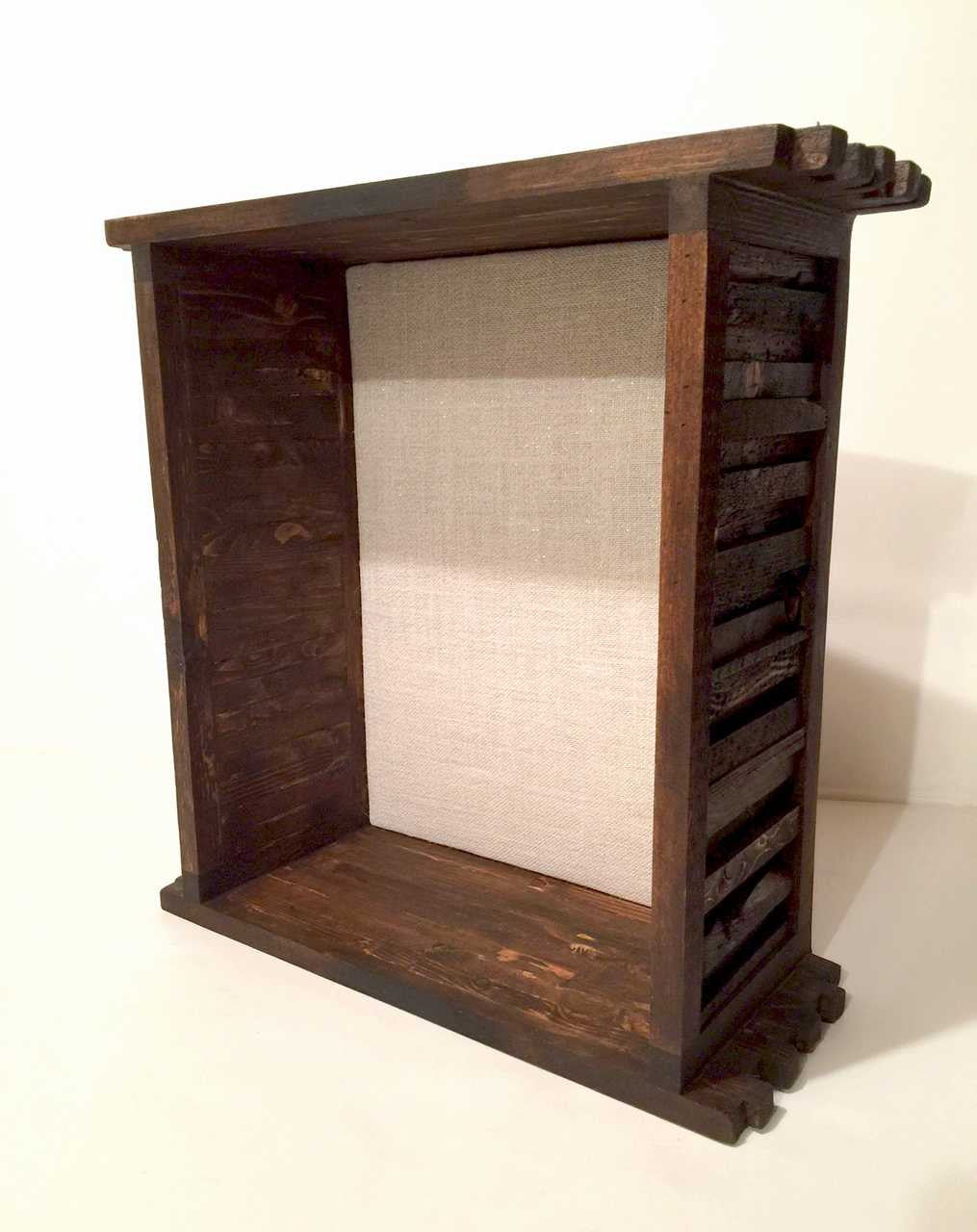 A brown shadow box with a shingled wood frame, clear glass window,and burlap backing on ivory background.