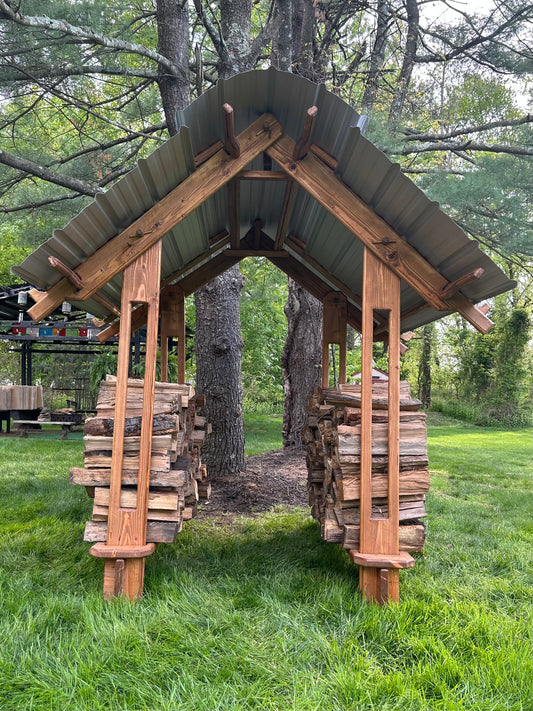 A handcrafted Mini Gazebo made from solid thermally modified wood with a galvanized steel roof, situated on a grassy area with trees in the background.